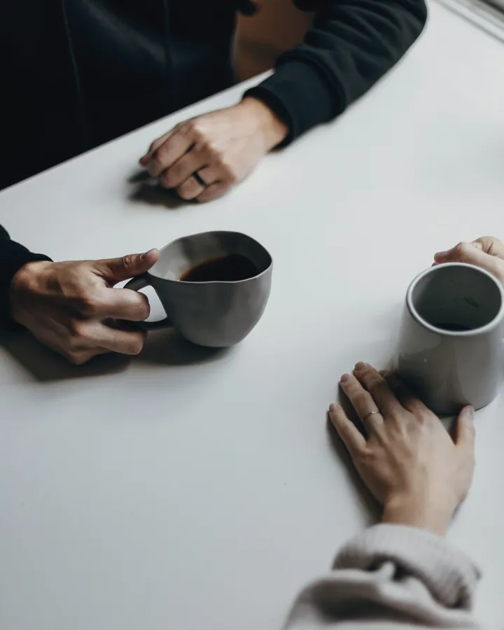 Two people talking over coffee at a white table