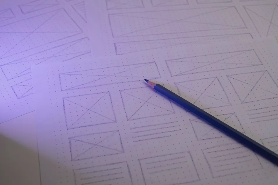 Pencil resting on a hand-drawn website wireframe
