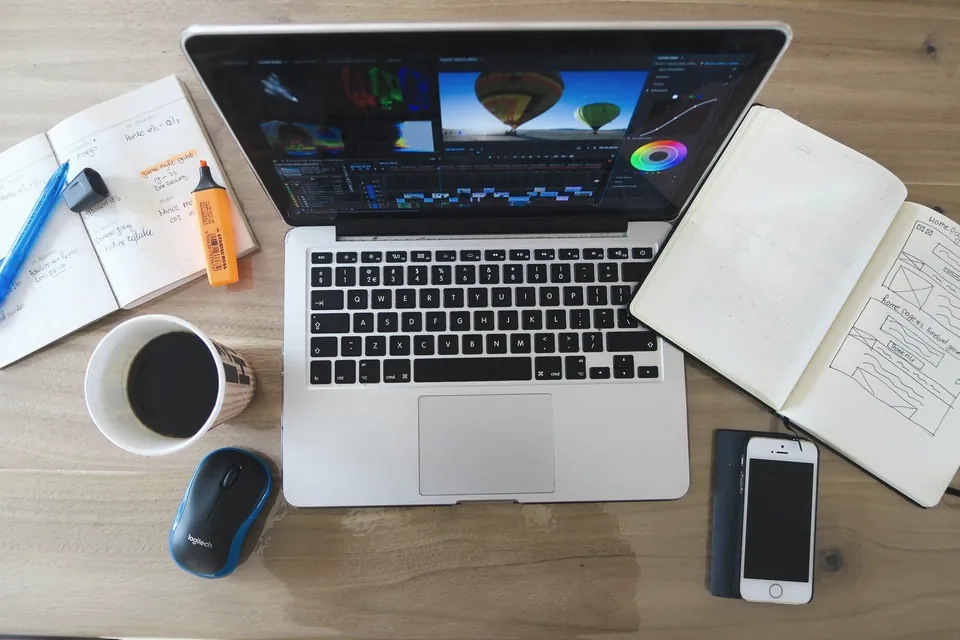 Laptop, notebooks and coffee on a work desk, seen from above
